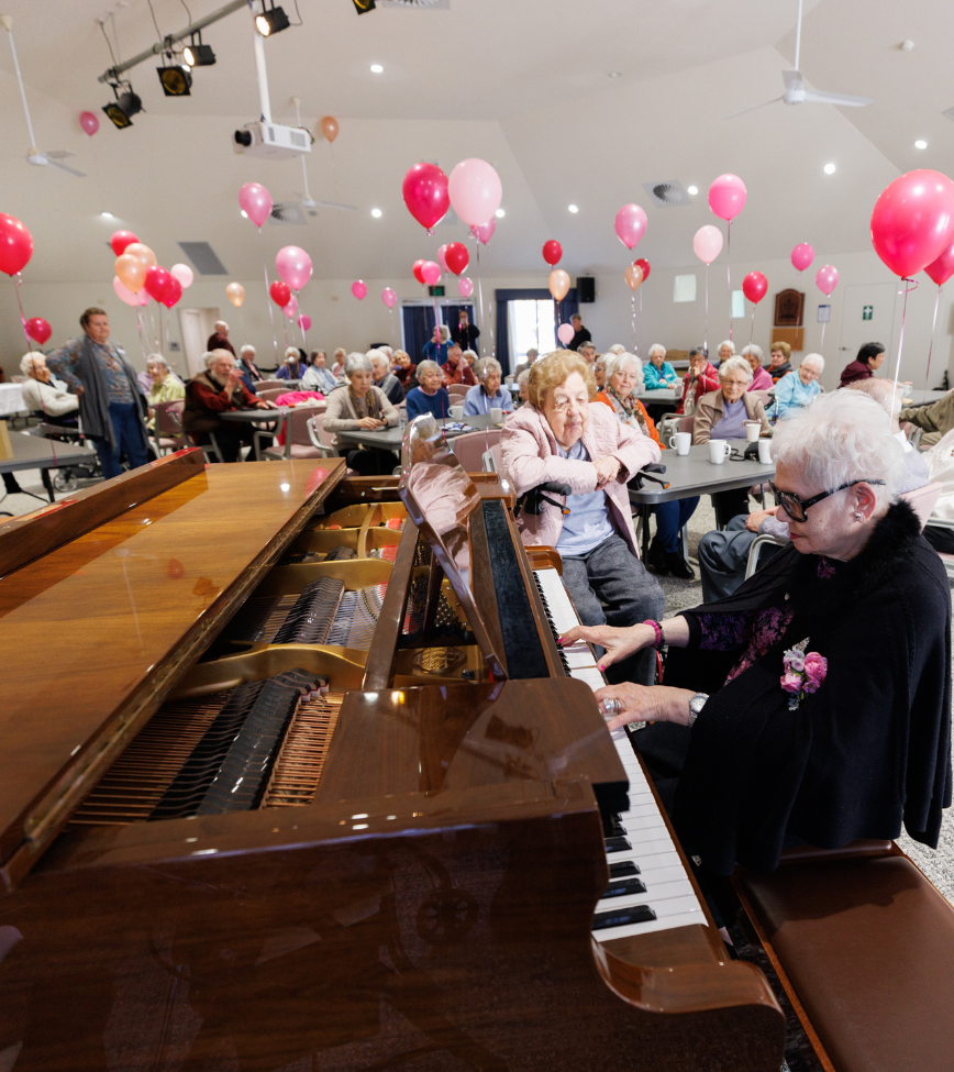 Gabrielle playing piano to Alan Walker Village residents