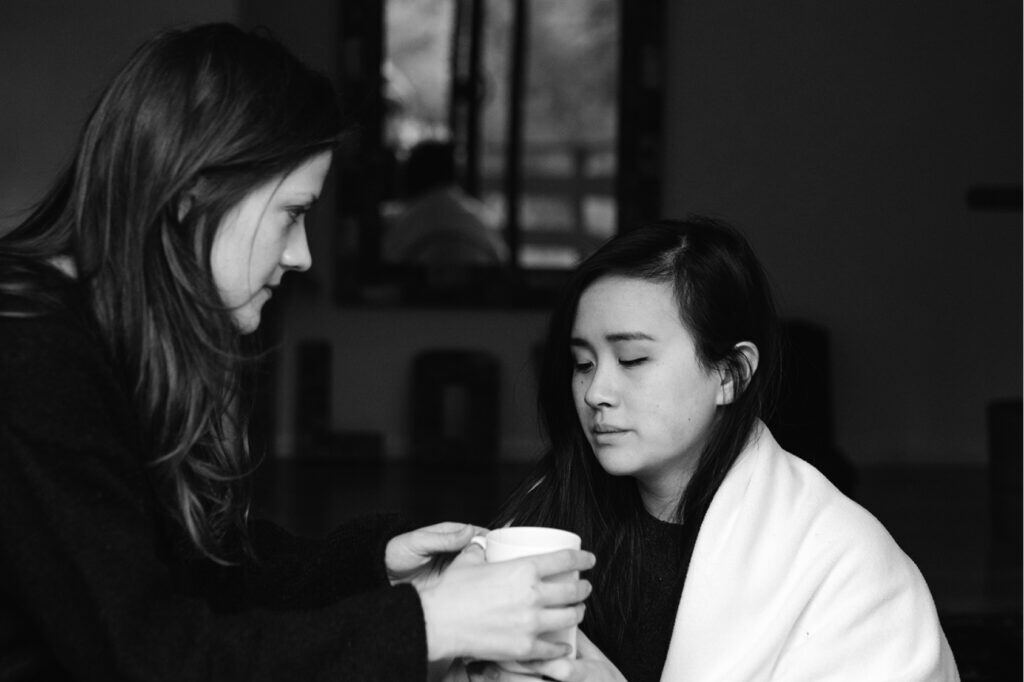 Woman handing take-away coffee to another woman