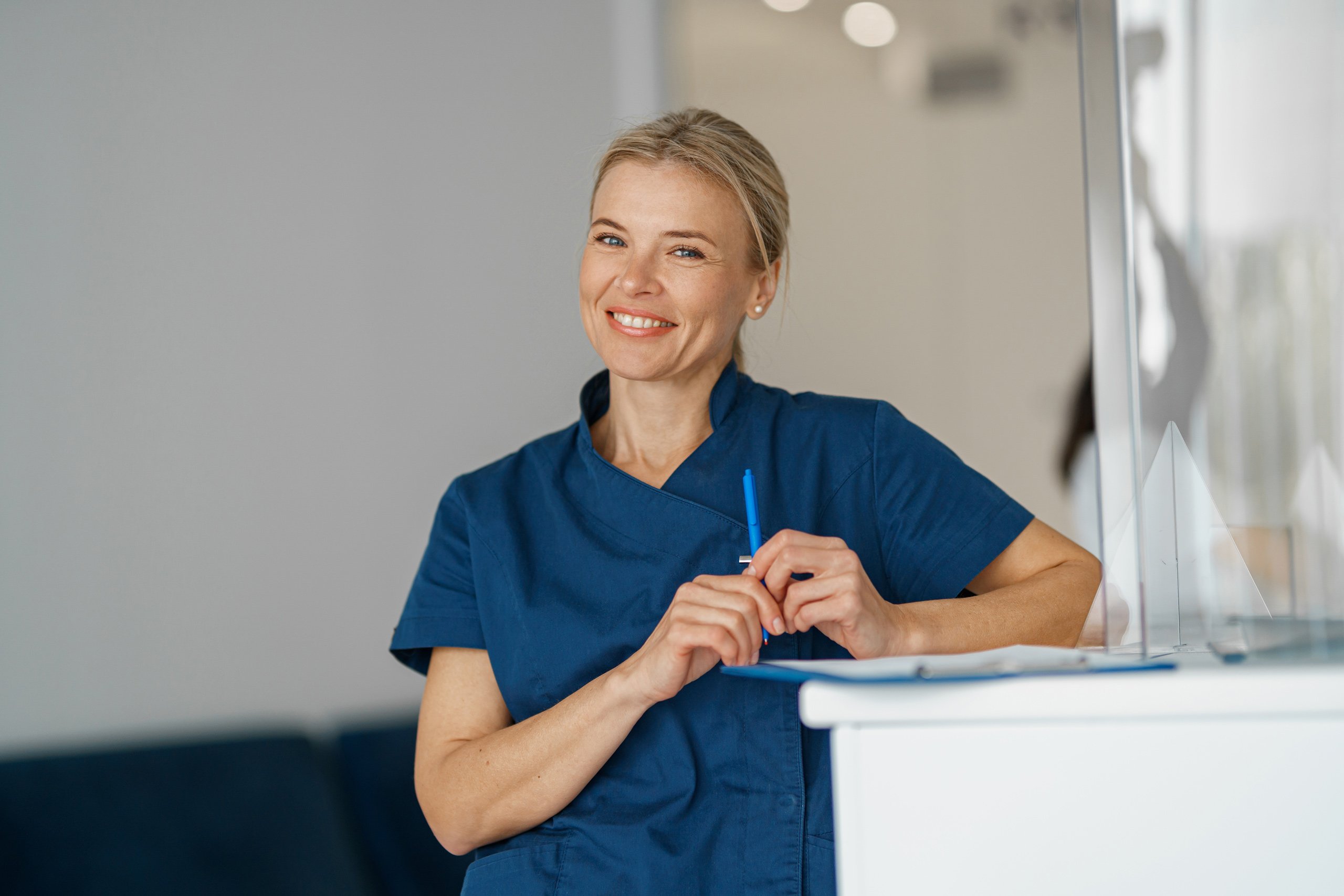 smiling-doctor-with-clipboard-standing-near-recept-2022-09-26-19-00-14-utc