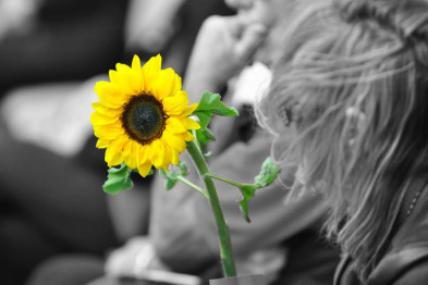 Woman holding a sunflower, symbolising hope and remembrance.