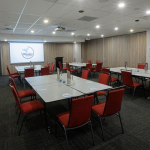 Medium side view shot of Pacific Room at the Wesley Conference Centre, with Wesley Mission logo showing on digital screen