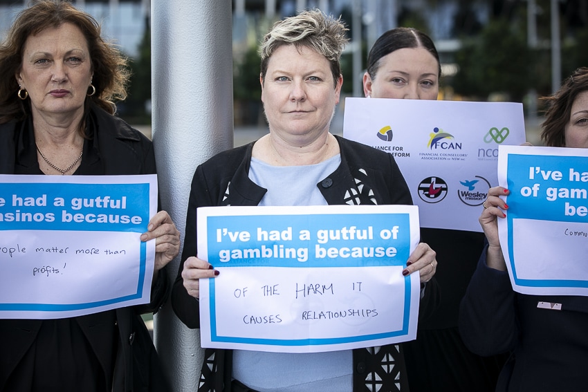 Three women holding a sign that says I've had a gutful of gambling because, followed by their reason