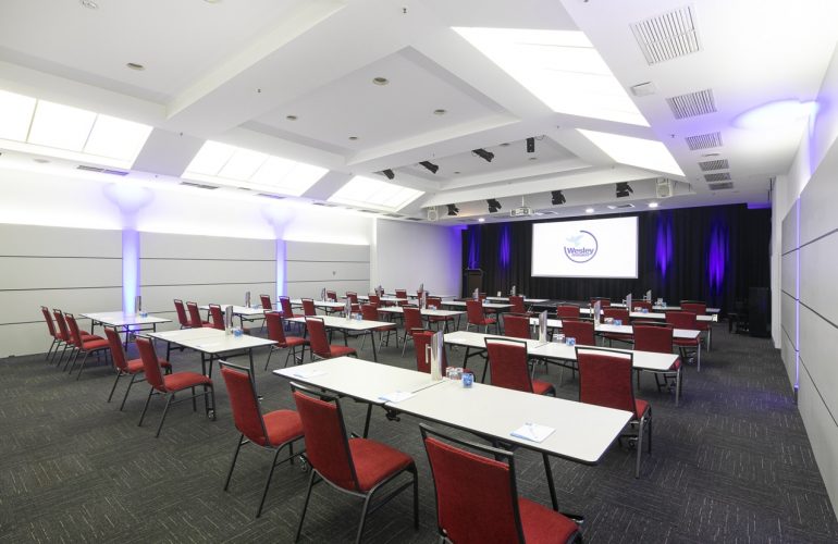 Medium side view shot of the Lyceum Room at the Wesley Conference Centre, with Wesley Mission logo showing on digital screen